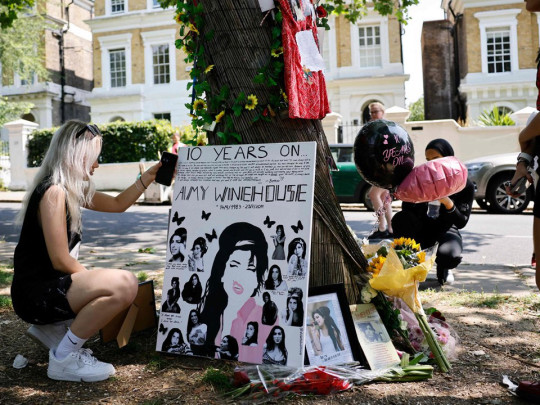 Amy Winehouse Fans Pay Tribute To Late Singer On 10th Anniversary Of Death Amy Winehouse’s family members and fans have gathered at the late singer’s home in North London to pay tribute to her on the 10th anniversary of her death. The musician died on July 23, 2011 at the age of 27 from alcohol poisoning. Pictures have shown a temporary shine situated outside of her house, where supporters have left flowers, balloons and other memorabilia to show their love for Amy. A group of fans also huddled together for a photo, as they posed with two posters which featured images of Amy alongside the words: ‘10 Years Without Amy’. Messages of condolences were also left at the shrine by some, with many expressing their sadness at how long it has been since the singer has gone. Other photos show fans standing alongside Amy’s statue, which is situated in Camden Town.